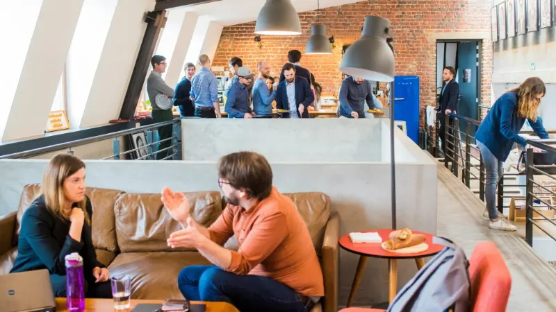 Colleagues talking in an open-plan office, for AWA’s Actis office relocation case study