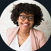 A smiling woman in glasses in front of a whiteboard